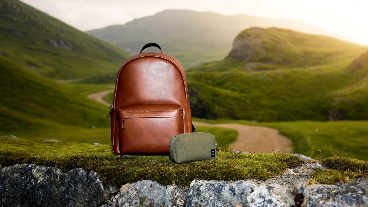 Rucksack und kleine Zubehörtasche auf einer bemoosten Steinmauer am Bergpfad